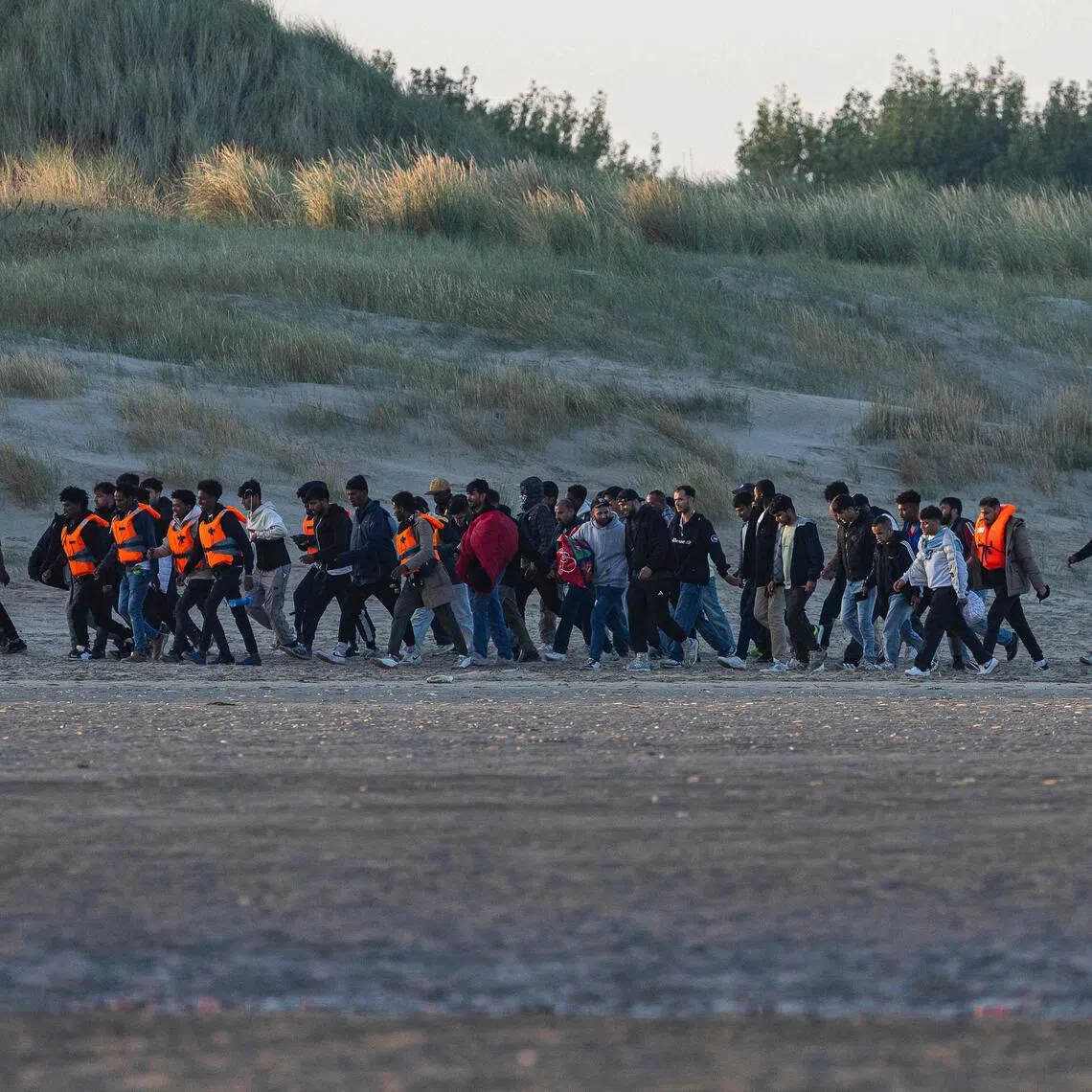 A 2025 photo shows migrants in northern France waiting for a smuggler’s boat so they can cross the English Channel to Britain.