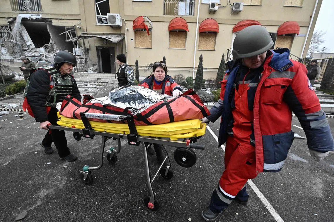 Ukrainian medics carry the body of a local resident killed after a Russian shelling in Kherson on Jan 29, 2023. 