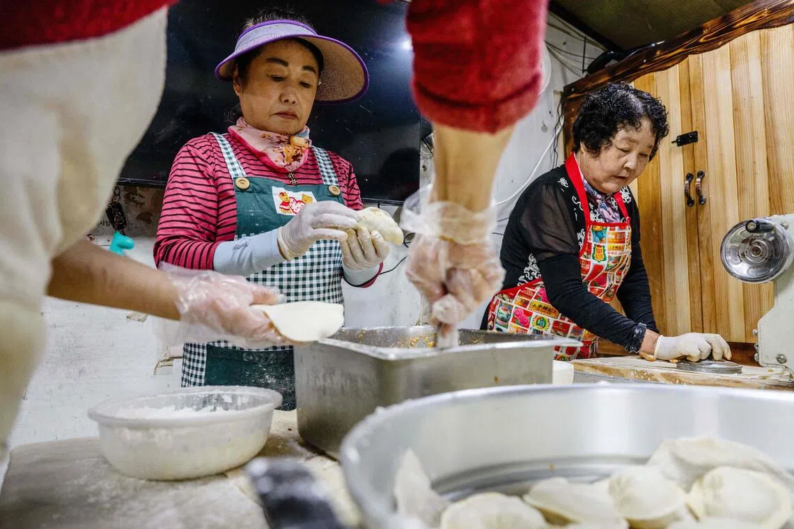 In this photo taken on October 7, 2025, employees of a food store make North Korean style mandu dumplings on Gyodong Island, roughly 2.3 kilometers from North Korea. Gyodong island, which sits at the mouth of the Han river, welcomed thousands of displaced people during the Korean War. Many crossed the water in small boats to Gyodong or swam across when Chinese forces, allied with the North Koreans, advanced on the town of Yeonbaek. Little did they know, this would be their last crossing. Most first-generation refugees have passed away, but a deep sorrow remains for the handful still alive. (Photo by ANTHONY WALLACE / AFP) / To go with AFP story SKorea-NKorea-conflict-refugee-politics, REPORTAGE