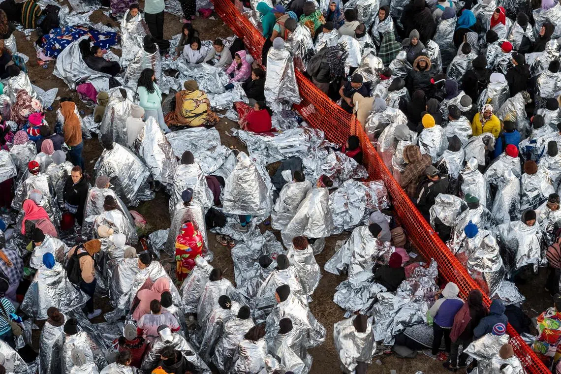 A aerial view of Immigrants wearing mylar blankets supplied by the U.S. Border Patrol to stay warm after spending the night outside a processing center near the U.S.-Mexico border on Dec 18. A surge as many as 12,000 immigrants per day crossing the U.S. southern border has overwhelmed U.S. immigration authorities in recent weeks.   