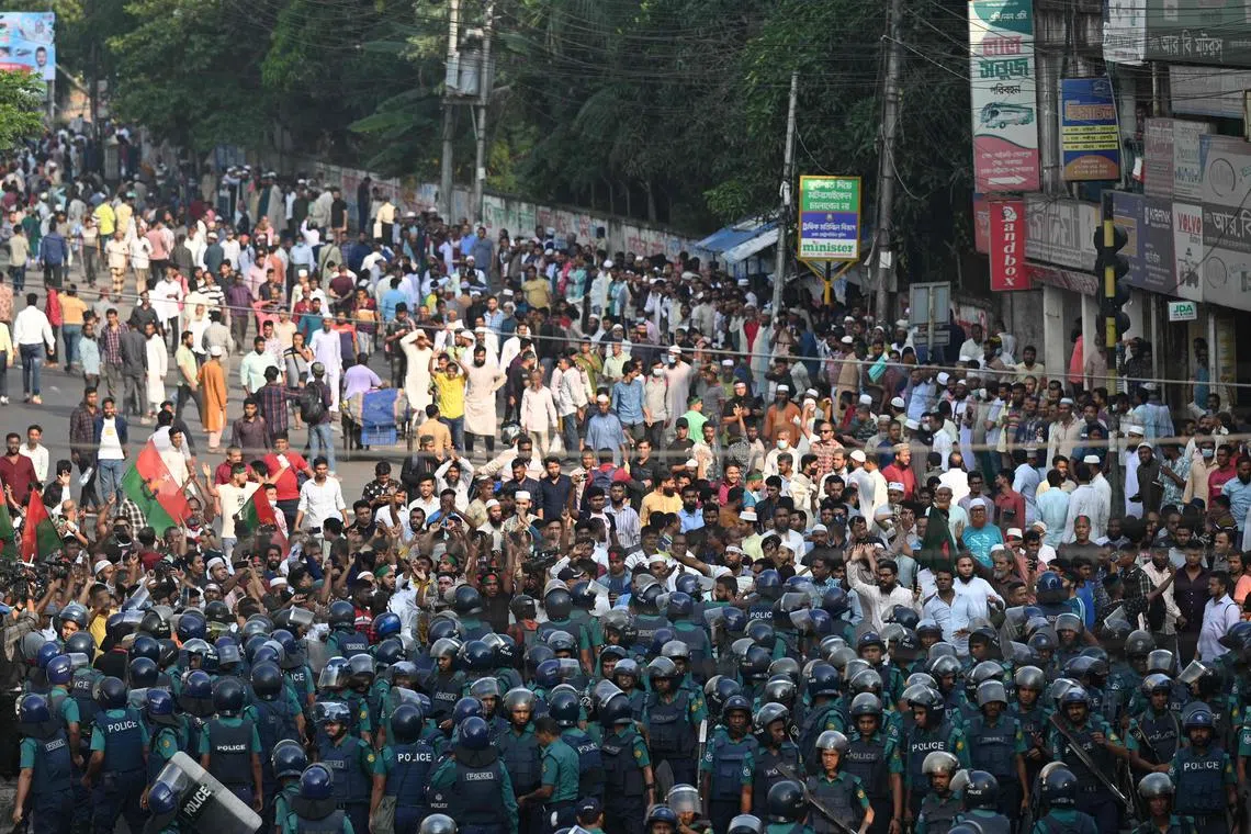 Police stand guard in front of Bangladesh Nationalist party (BNP) supporters during a rally demanding the resignation of the current government.