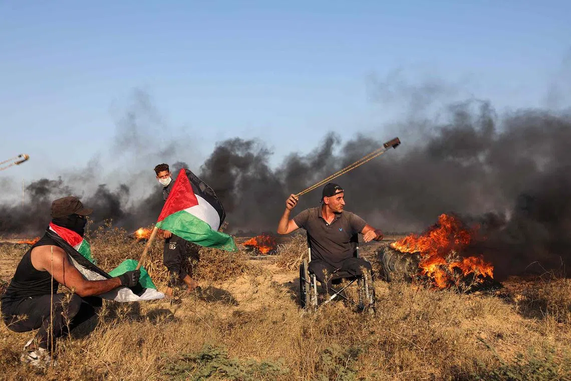 A Palestinian demonstrator uses a slingshot to hurl rocks towards Israeli soldiers during a rally near the Israel-Gaza border fence east of Gaza City on Sept 22.