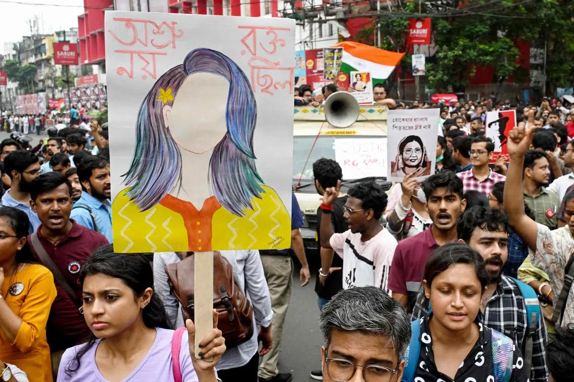 A woman holds a portrait (L) depicting the female medic victim during a rally by doctors and social activists to condemn the rape and murder of a doctor in Kolkata on Oct 2.