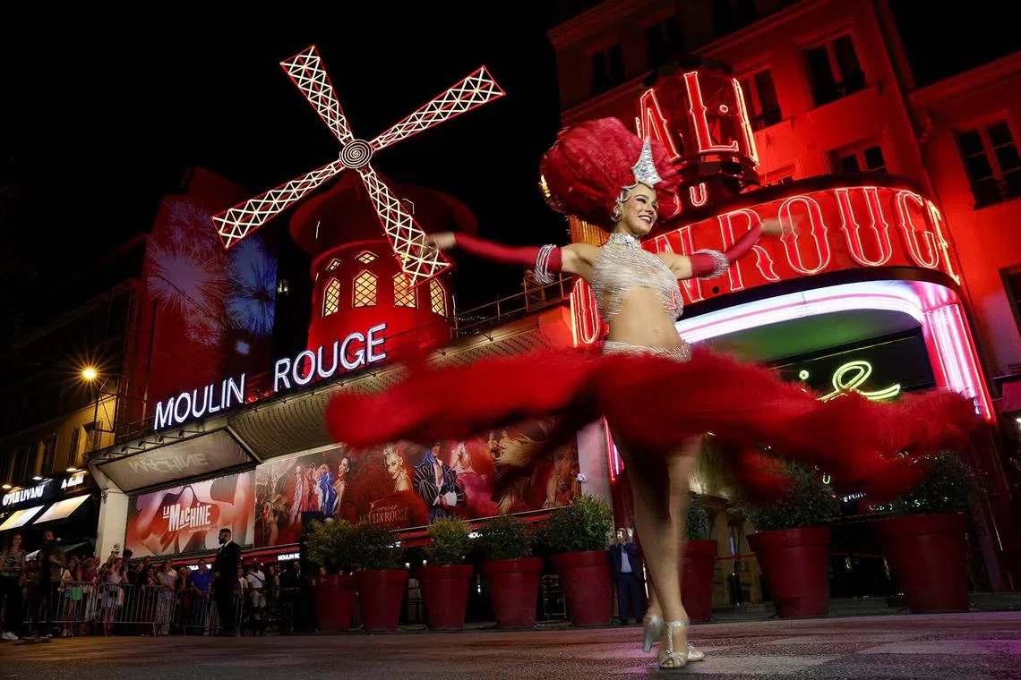 A French Cancan dancer performing in front of the Moulin Rouge cabaret during celebrations marking the restart of its iconic windmill with red sails, in Paris, France, July 10, 2025. 