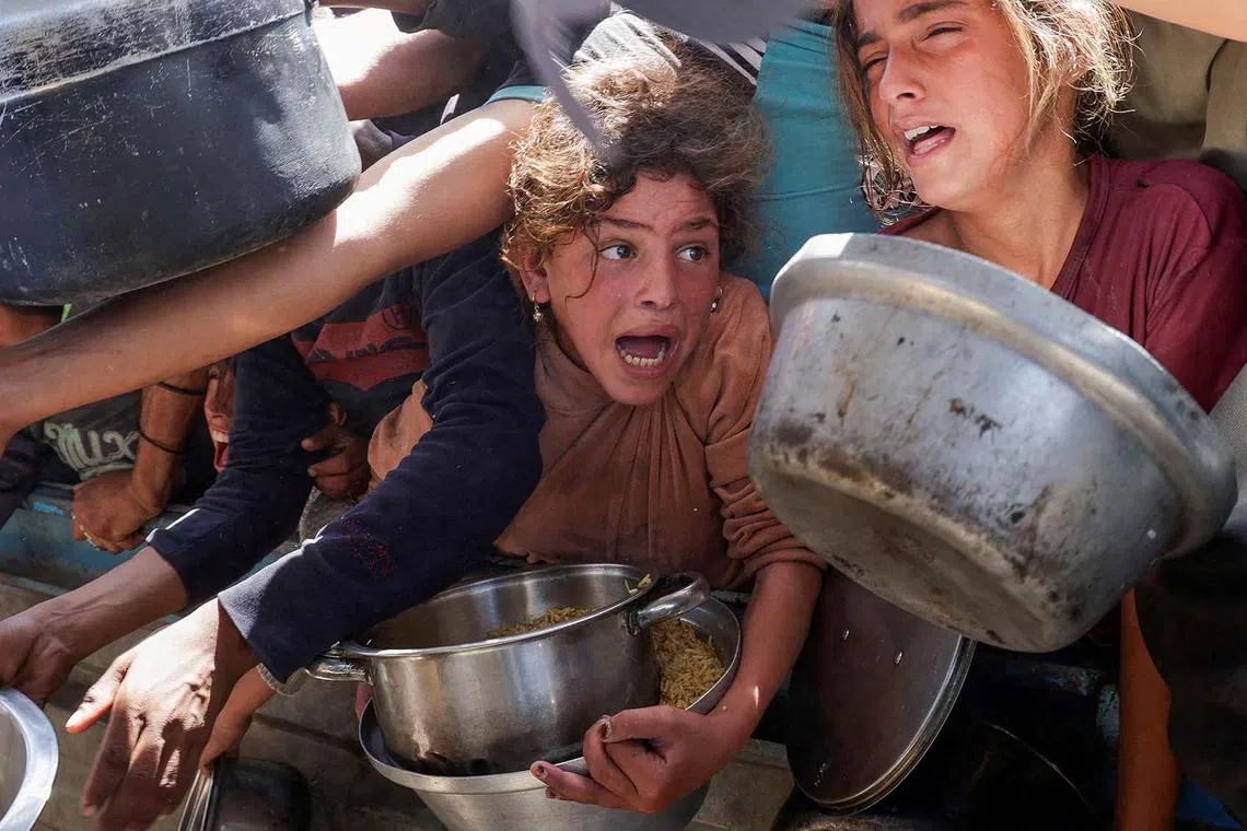 Palestinians jostling for food cooked by a charity kitchen, in Khan Younis, southern Gaza Strip, April 29, 2025. 