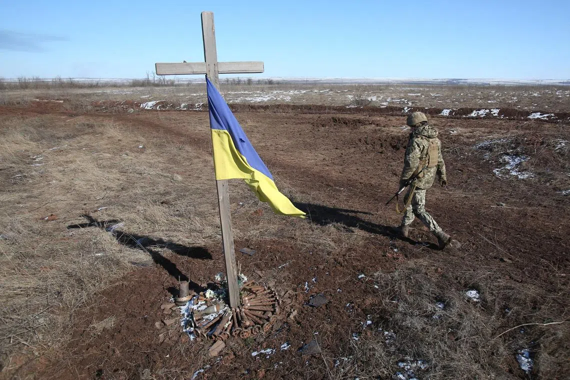 A Ukrainian soldier walks past a makeshift memorial to fallen soldiers in Ukraine's  Donetsk region.