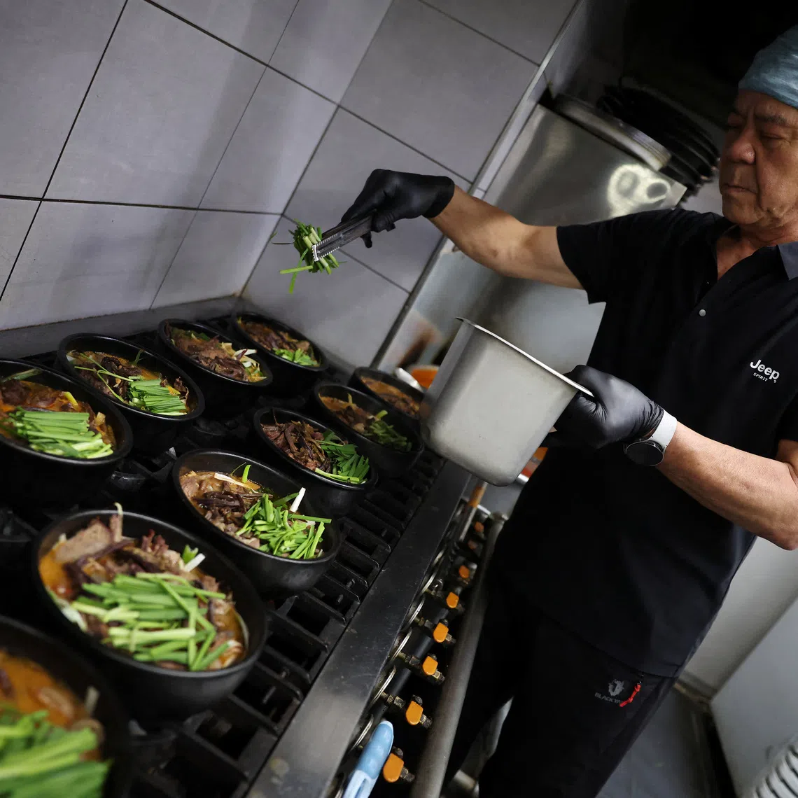 Lee Kang-chun, a restaurant owner who sells dog meat and black goat meat stews, cooks dishes during Malbok, the last of Korea’s traditional hottest days of summer, at his restaurant in South Korea.