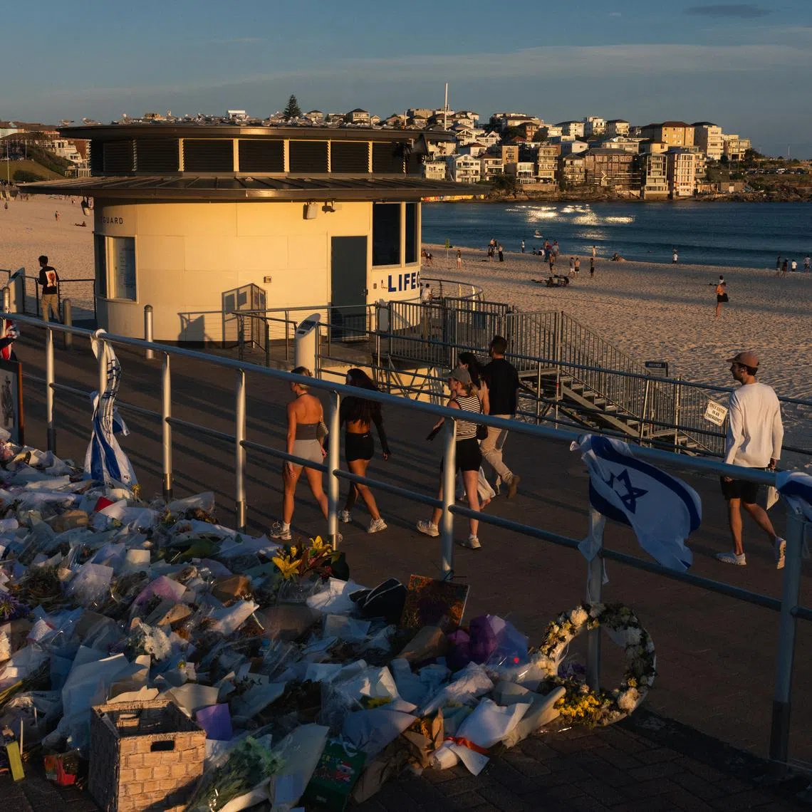 People walk past a wall of flowers left in memory of mass shooting victims at Bondi Beach in Sydney, on Dec 20, 2025.