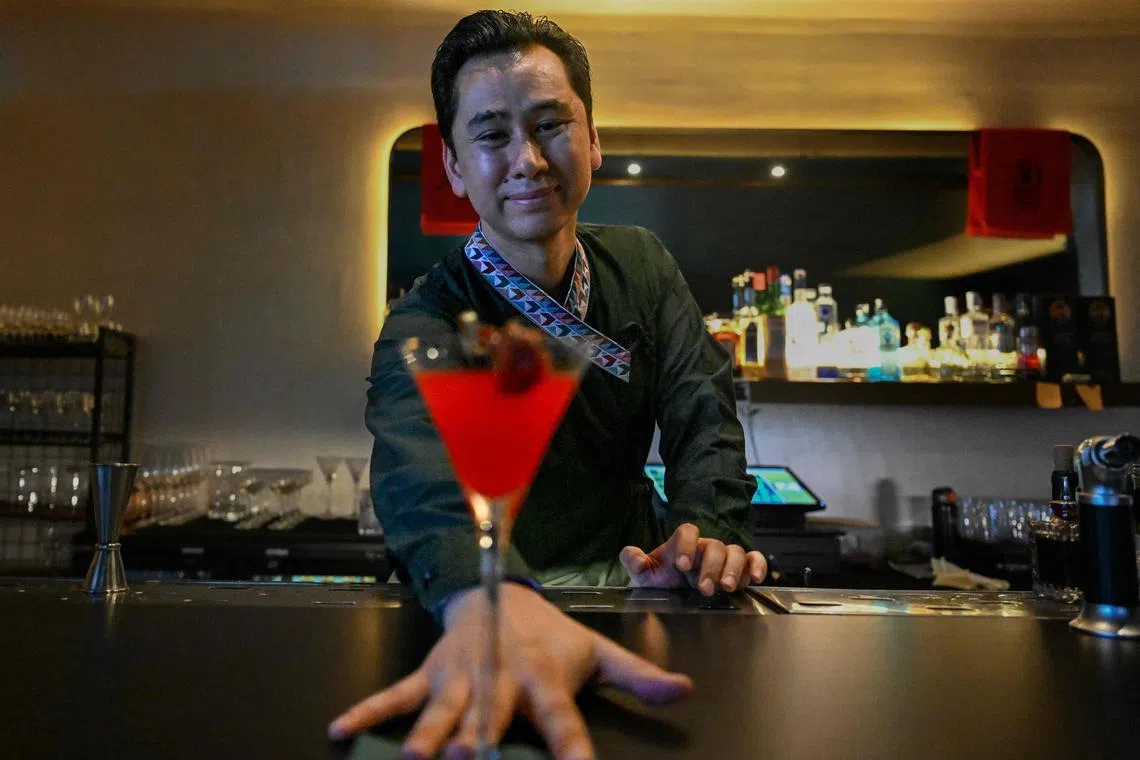 In this photograph taken on July 2, 2025, Abhishek Tuladhar, founder of cocktail bar and restaurant Barc, serves a drink with a slice of titaura, a local tangy and spicy hog plum treat, in a martini glass during an interview with AFP in Kathmandu. Until recently, cocktails were an afterthought on most bar menus in the capital of the Himalayan nation, often overshadowed by beers or straight spirits. But over the past five years, the city's cocktail scene has changed, led by a new generation of bartenders turning global experience into local innovation as a new wave of Nepali cocktail bars combines age-old techniques with local traditions crafting uniquely Nepali drinks to make a global mark. (Photo by Prakash MATHEMA / AFP) / To go with 'Nepal-Lifestyle-Drink', FOCUS