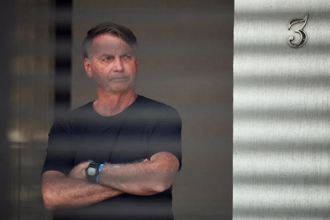 FILE PHOTO: Brazil's former President Jair Bolsonaro stands at his home while under house arrest, ordered by Supreme Court Justice Alexandre de Moraes, as he awaits trial over an alleged plot to overturn the 2022 election, in Brasília, Brazil, August 14, 2025. REUTERS/Adriano Machado/File Photo