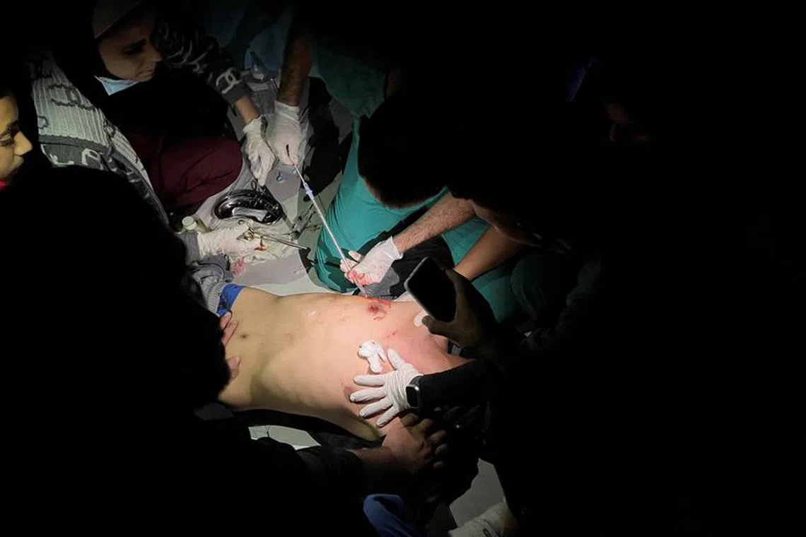 Medical services use phone flashlights to assist a Palestinian wounded in Israeli strikes at the Indonesian hospital after Al Shifa hospital has gone out of service amid Israeli ground offensive, in the northern Gaza Strip November 16, 2023. REUTERS/Fadi Alwhidi