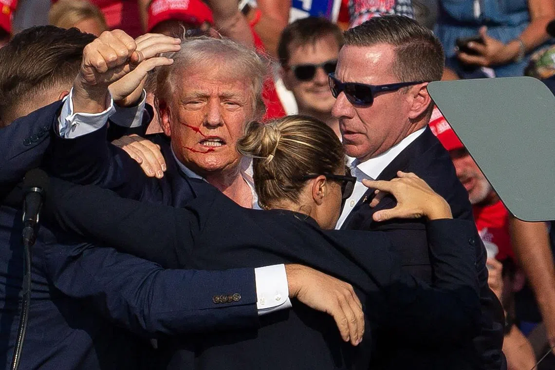 US Republican candidate Donald Trump is seen with blood on his face and surrounded by secret service agents as he is taken off the stage at a campaign event in Butler, Pennsylvania, on July 13 after being shot in the ear. 