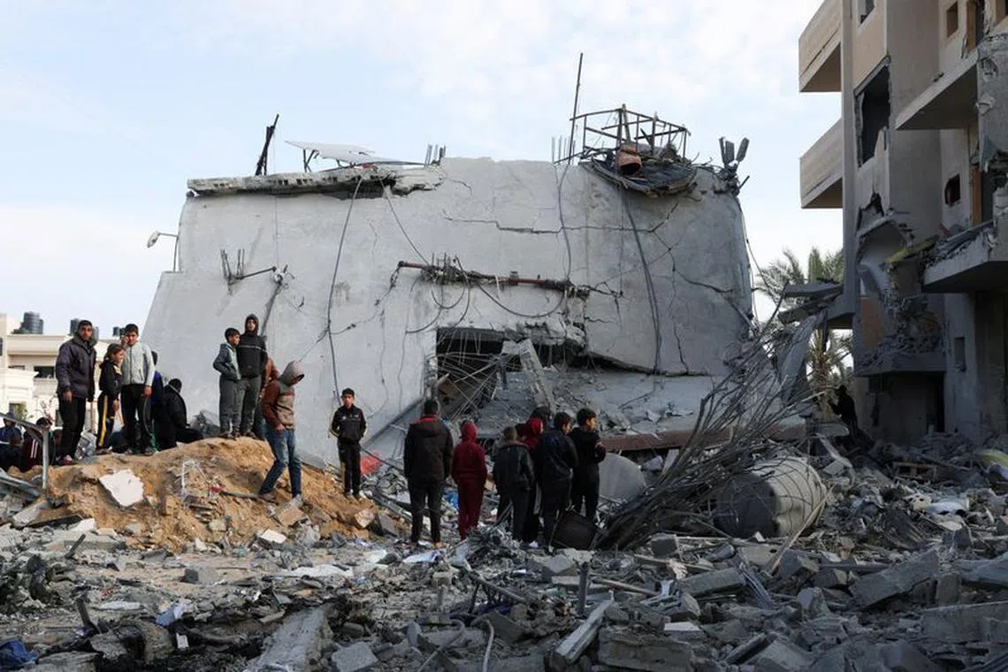 FILE PHOTO: Palestinians gather near a house hit by an Israeli strike, in Rafah in the southern Gaza Strip February 16, 2024. REUTERS/Ibraheem Abu Mustafa/File Photo