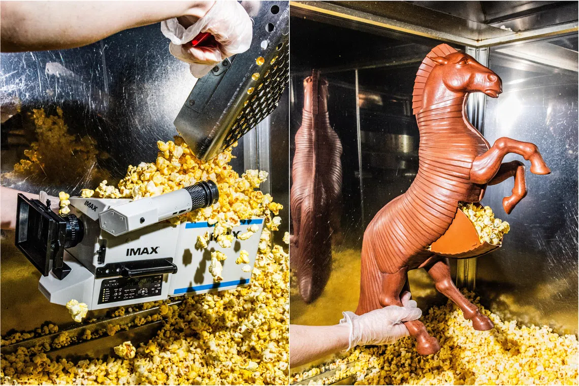 (From left) A popcorn bucket replica of the IMAX camera used by Christopher Nolan and a 22-inch popcorn bucket rendering of the Trojan horse in The Odyssey.