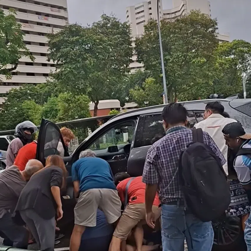 After the boy is freed, a few men are seen carrying him to the side of the road while others gather around to assist.