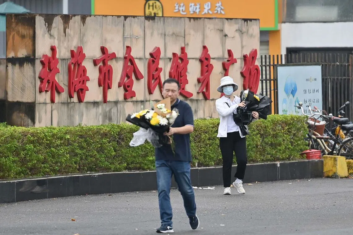 Workers removing flowers from a makeshift memorial outside the Zhuhai Sports Centre in Zhuhai, in China's Guangdong province, on Nov 13, 2024, two days after 35 people were killed when a man drove a car into a crowd in one of the country's deadliest mass-casualty events in years.