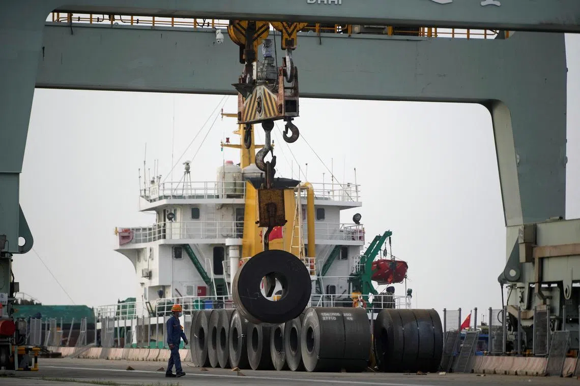 An employee walks past rolled steel at a port during a government-organised media tour to Baoshan Iron & Steel Co., Ltd. (Baosteel) in Shanghai, China on Sept 16, 2022. 