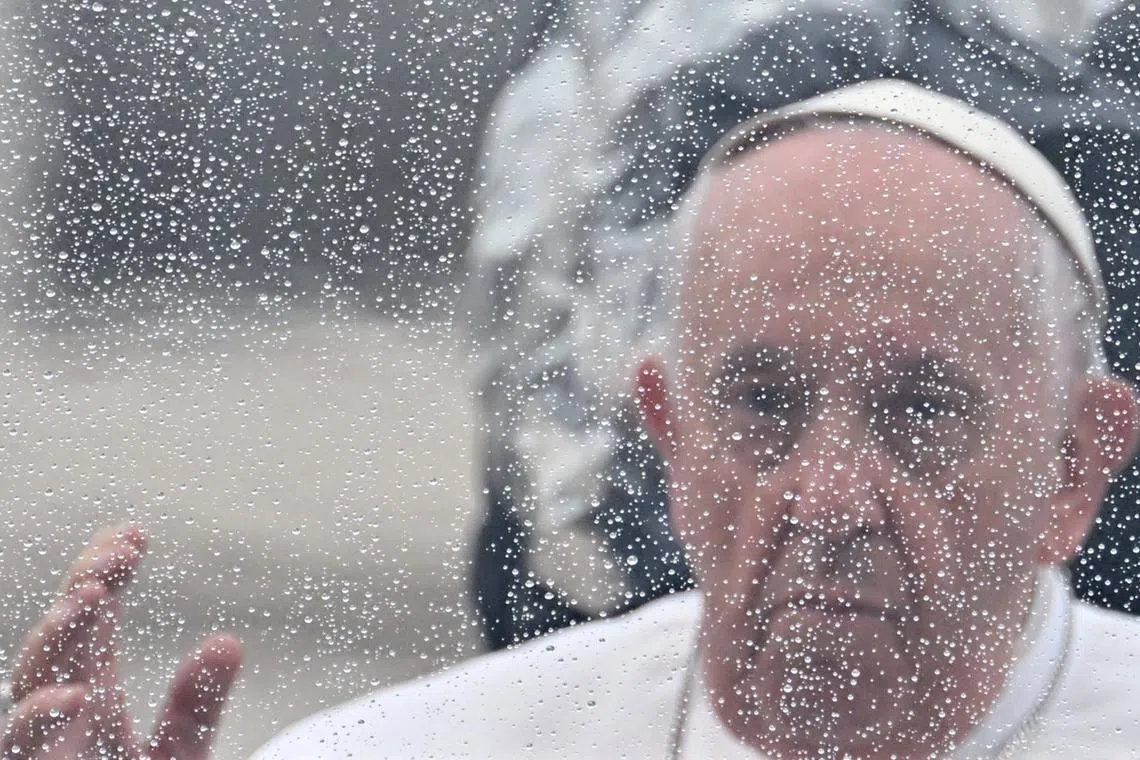 Pope Francis, pictured through the windshield of the popemobile car, waving as he arrives under the rain for the weekly general audience on May 10 at St. Peter's square in The Vatican. 