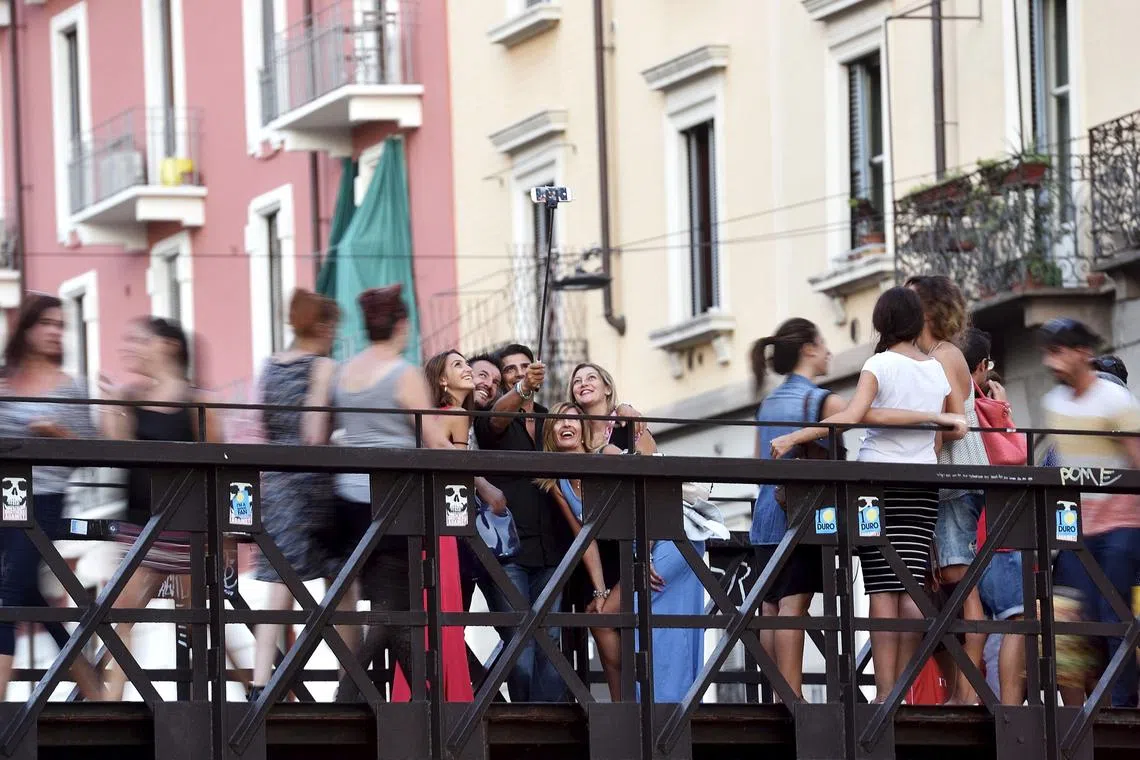 FILE PHOTO: People take a selfie at Naviglio Gran Canal in Milan, August 29, 2015. REUTERS/Flavio Lo Scalzo/File Photo