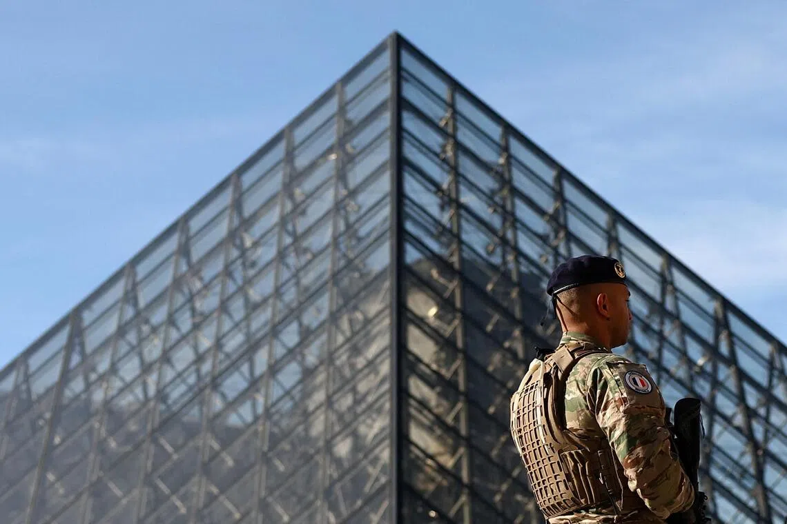 A French soldier from the "Sentinelle" security plan patrols past the glass Pyramid of the Louvre Museum as French police have arrested more suspects linked to the theft of treasures from the Louvre museum's Galerie d'Apollon (Apollo gallery), in Paris, France, October 30, 2025. REUTERS/Abdul Saboor