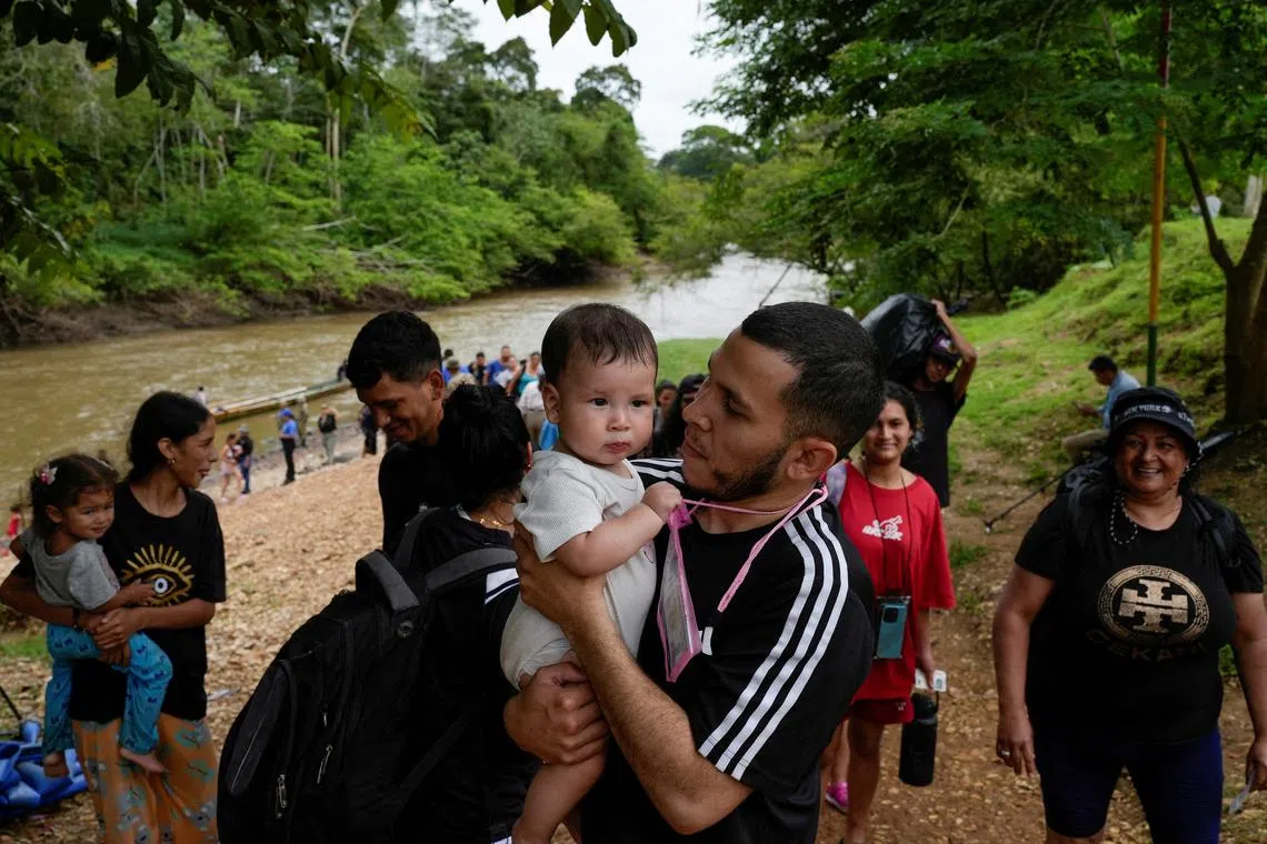 FILE PHOTO: A migrant carries his child after crossing the Darien Gap and arriving at the migrant reception center, in the village of Lajas Blancas, Darien Province, Panama, September 26, 2024. REUTERS/Enea Lebrun/File Photo