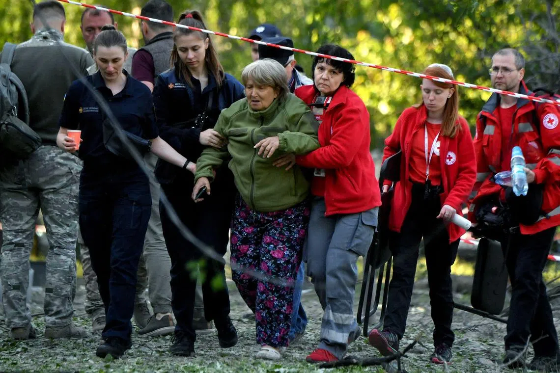 Rescuers help an elderly woman whose daughter and granddaughter died as a result of a Russian missile being downed outside a clinic in Kyiv.