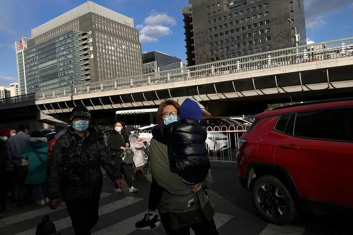 A woman carrying a child walks outside a children's hospital in Beijing.