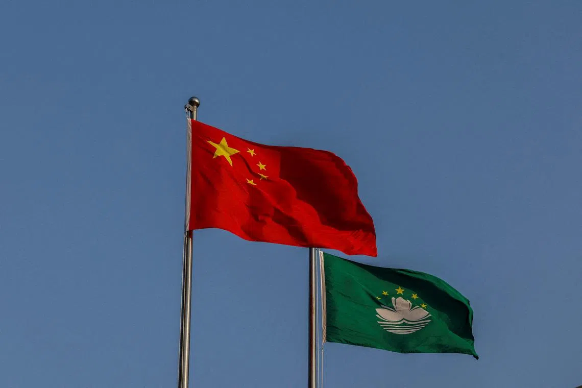 FILE PHOTO: Chinese and Macau flags flutter during a flag-raising ceremony at the Golden Lotus Square to mark the 25th anniversary of Macau's handover from Portugal to China, in Macau, China December 20, 2024. REUTERS/Tyrone Siu/File Photo