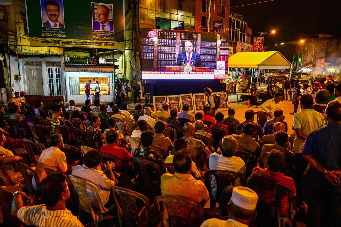 People watch a live telecast as Sri Lanka's President Ranil Wickremesinghe addresses the nation in Colombo on June 26.
