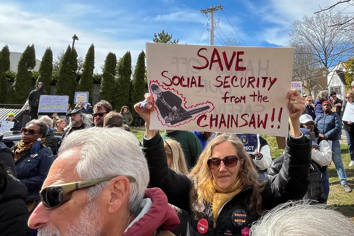 FILE PHOTO: A woman holds a sign during a protest against cuts made by U.S. President Donald Trump's administration to the Social Security Administration, in White Plains, New York, U.S., March 22, 2025. REUTERS/Nathan Layne/File Photo