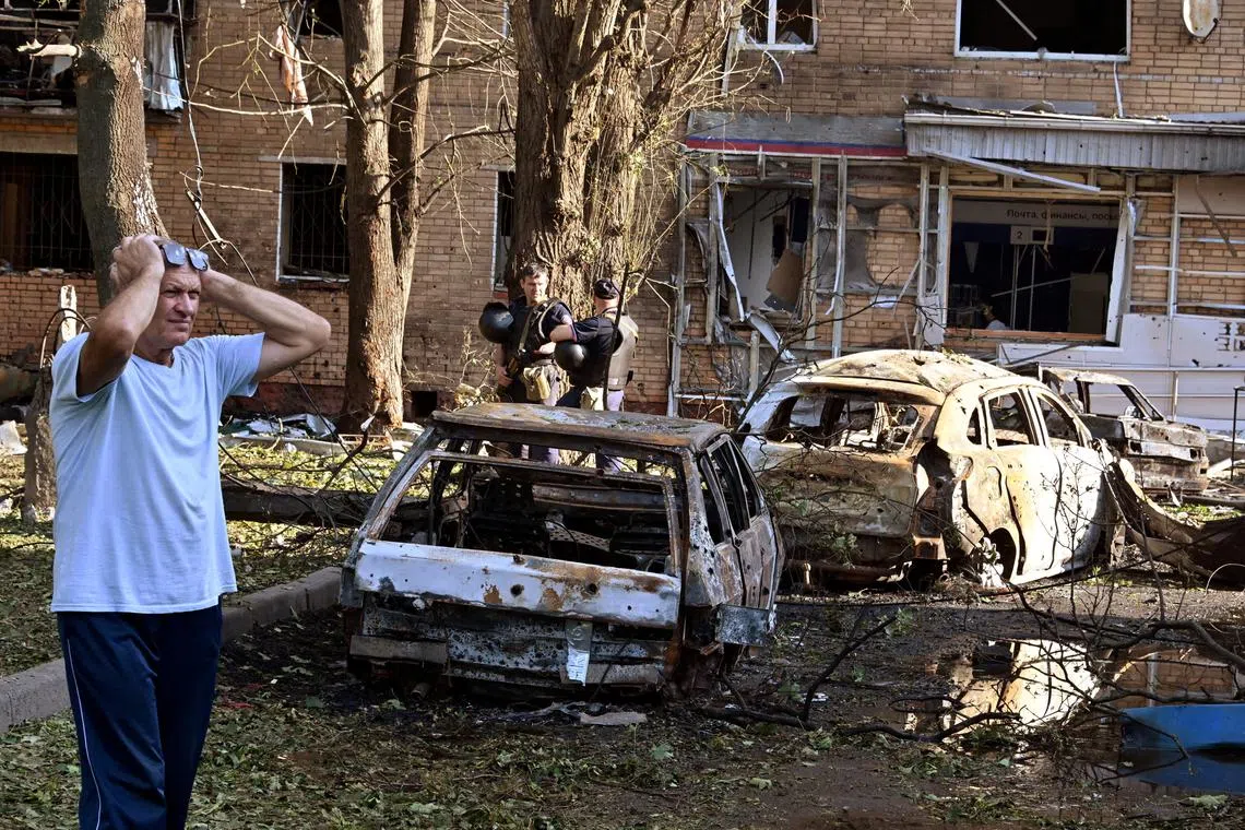 A man reacts while standing next to burnt-out remains of cars in the courtyard of a multi-storey residential building, which according to local authorities was hit by debris from a destroyed Ukrainian missile, in the course of Russia-Ukraine conflict in Kursk, Russia August 11, 2024. Kommersant Photo/Anatoliy Zhdanov via REUTERS RUSSIA OUT. NO COMMERCIAL OR EDITORIAL SALES IN RUSSIA.