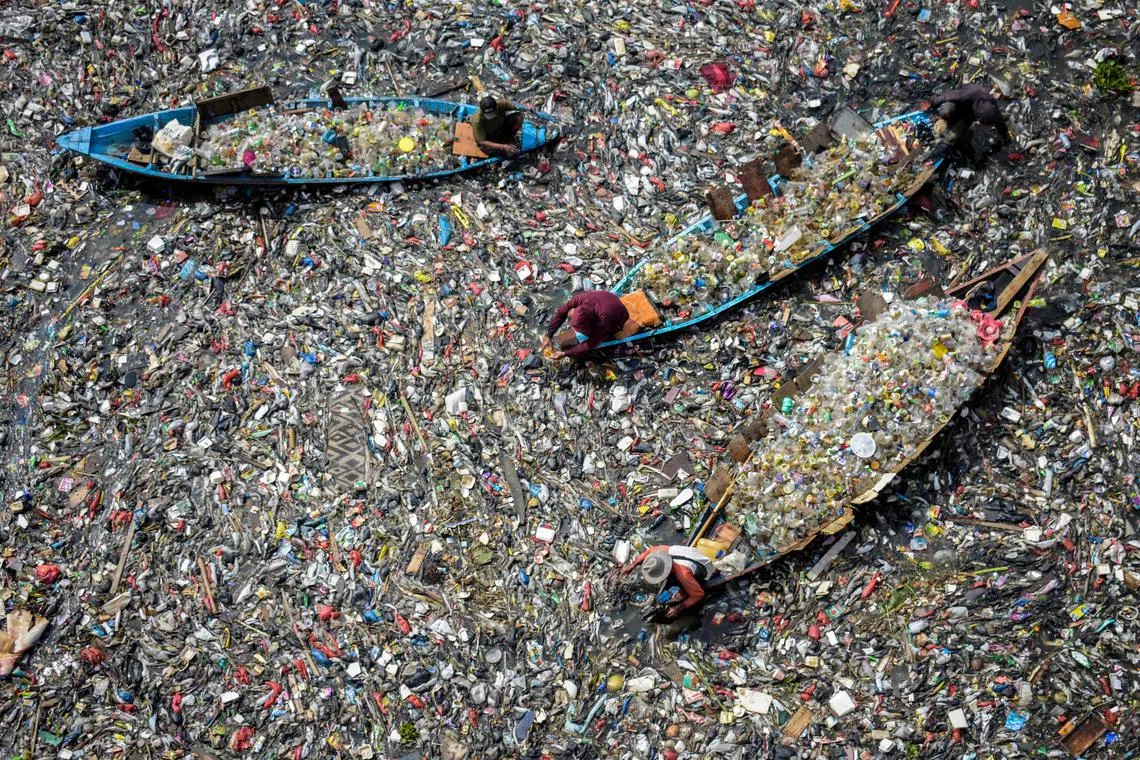 (FILES) People on boats collect recyclable plastics from the heavily polluted Citarum River at Batujajar in Bandung, West Java, on June 12, 2024. It has been two years since the UN first agreed to work towards the world's first treaty to end plastic pollution, and negotiators have met four times already to hammer out details. But observers say progress on substance has been painfully slow -- and at times actively stymied by countries keen to water down any final treaty. (Photo by TIMUR MATAHARI / AFP) / To go with UN-environment-plastics-synthetics-diplomacy by Sara Hussein