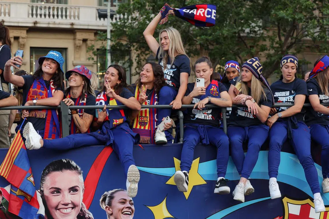 TOPSHOT - Barcelona's Spanish midfielder Alexia Putellas (C) and the rest of players of FC Barcelona women football team parade aboard a open-top bus preceded by the men's team (out of frame), to celebrate their La Liga titles in Barcelona on May 15, 2023. The FC Barcelona women's team won its fourth consecutive La Liga title on April 30 after scoring 3-0 against Sporting de Huelva at the Estadi Johan Cruyff while the men's team yesterday won their 27th La Liga championship by thrashing Espanyol 4-2, wrestling the title back from rivals Real Madrid. (Photo by Lluis GENE / AFP)