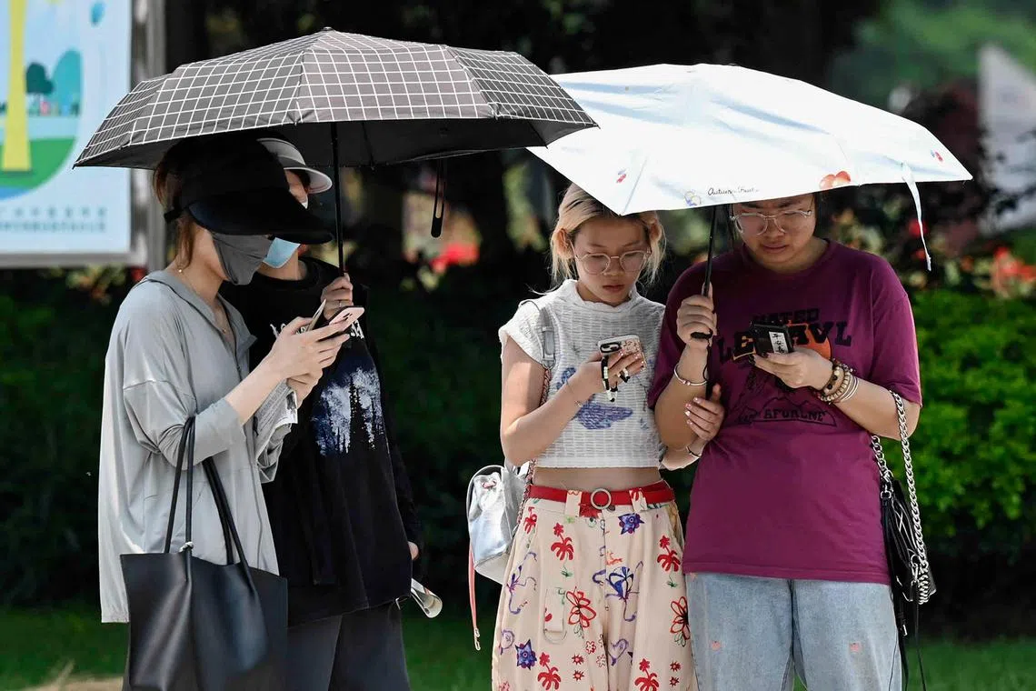 People use umbrellas to shelter from the sun amid hot weather in Guangzhou, in China's southern Guangdong province.