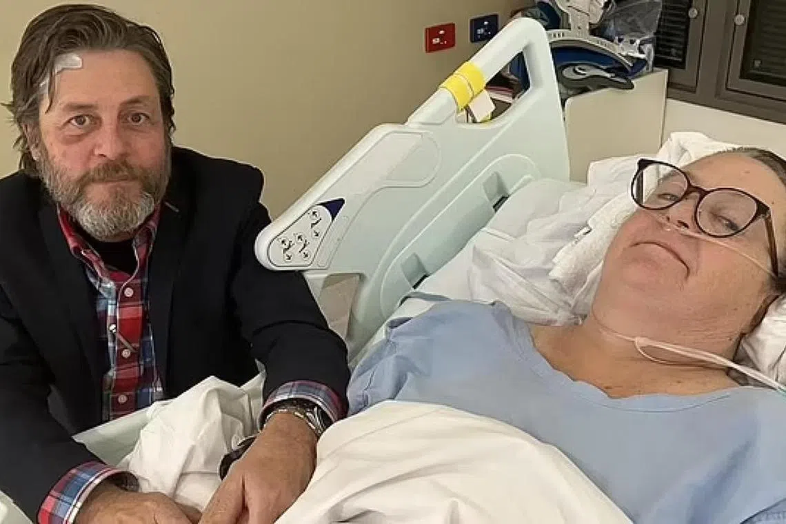 Ms Kerry Jordan is left paralysed from the chest down as a result of a spine injury when Singapore Airlines flight 321 struck turbulence. She is pictured in the hospital with husband Keith Davis.