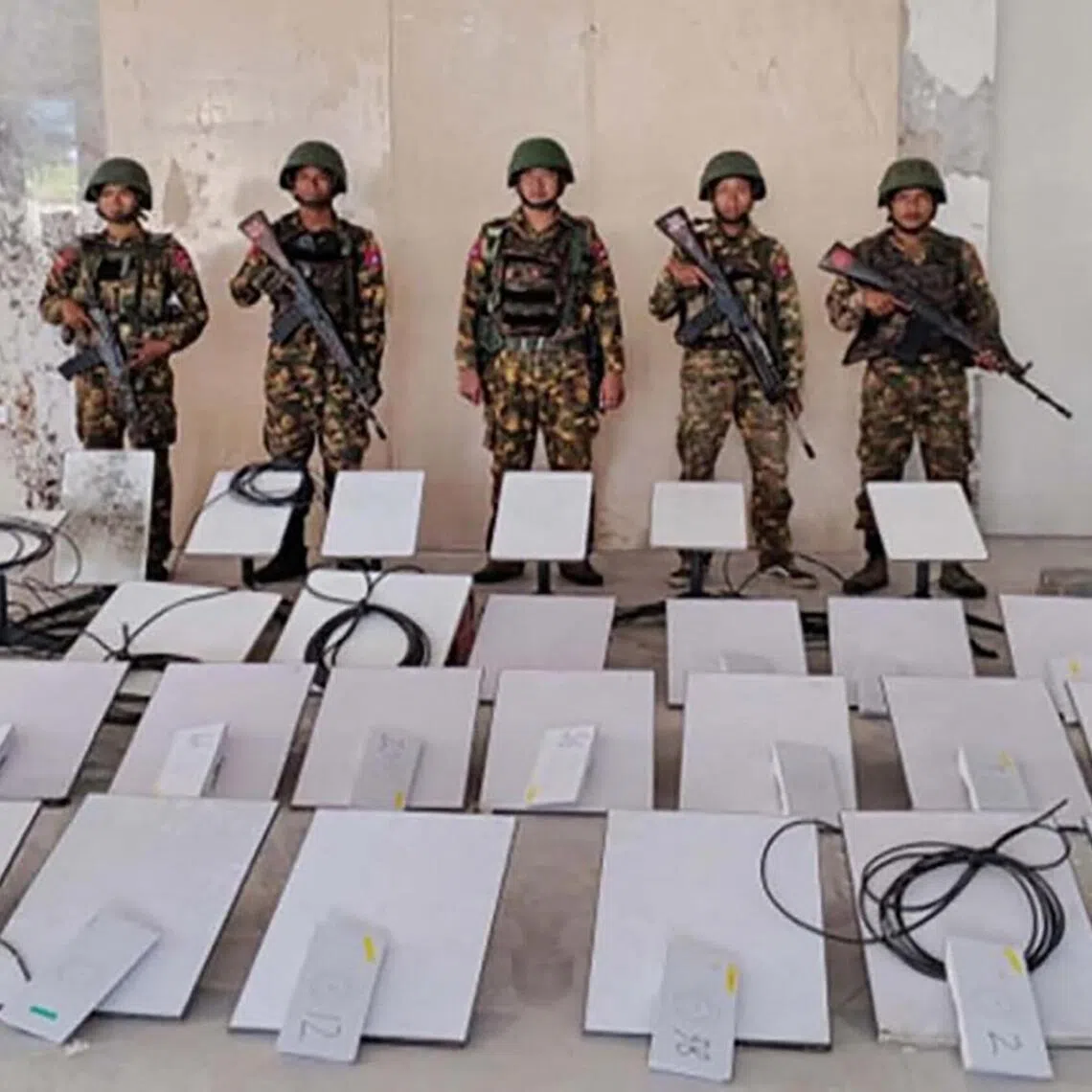 This handout photo taken on October 20, 2025 and released on October 22, 2025 by the Myanmar Military Information Team shows members of Myanmar’s military standing next to Starlink devices seized during a raid on the KK Park online scam centre in Myawaddy, Myanmar’s Kayin State. SpaceX has cut service to more than 2,500 Starlink devices at Myanmar scam centres, a company executive said October 22, after AFP revealed that their use had exploded in the illicit industry. Myanmar's military earlier on October 20 announced it had raided the KK Park scam centre and seized 30 Starlink satellite internet terminals. (Photo by Handout / MYANMAR MILITARY INFORMATION TEAM / AFP) / RESTRICTED TO EDITORIAL USE - MANDATORY CREDIT "AFP PHOTO / MYANMAR MILITARY INFORMATION TEAM" - NO MARKETING - NO ADVERTISING CAMPAIGNS - DISTRIBUTED AS A SERVICE TO CLIENTS