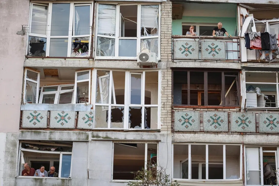 Residents stand on the balconies of an apartment building damaged by a Russian drone strike, in the city of Chornomorsk, in Ukraine's Odesa region.