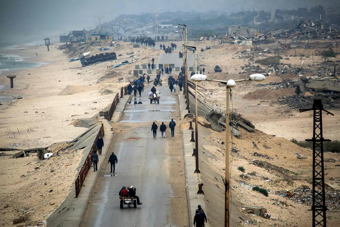 TOPSHOT - People walk along the Wadi Gaza bridge along al-Rashid street across the Netzarim corridor between Gaza City (top) and Nuseirat (bottom) in the central Gaza Strip on February 10, 2025 as displaced people return home amid the current ceasefire deal in the war between Israel and Hamas. (Photo by Eyad BABA / AFP)