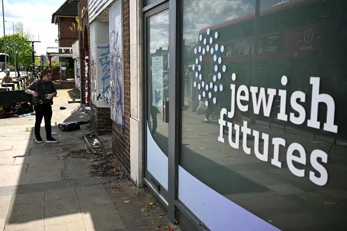 A police officer looks at a glass bottle during an investigation into an arson attack in Hendon, north London on April 18, 2026. 