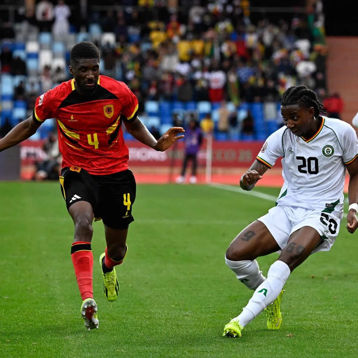 Zimbabwe forward Tawanda Chirewa crosses the ball past Angola defender Clinton Mata in the Africa Cup of Nations (CAN) Group B football match between at Marrakesh Stadium on Dec 26, 2025.