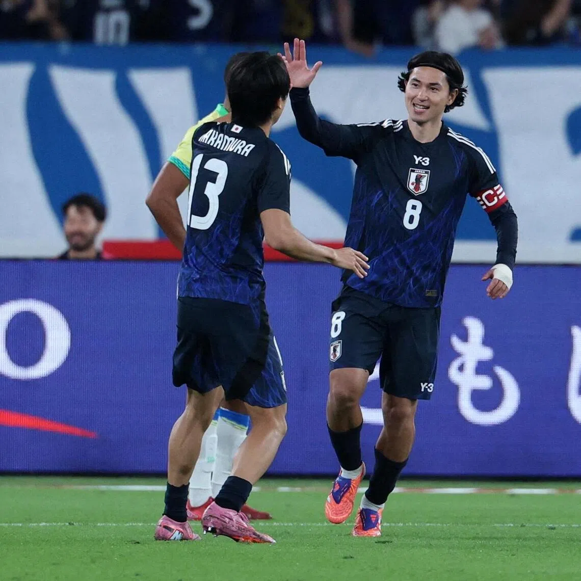 Japan's Takumi Minamino celebrates scoring their first goal with Keito Nakamura in an international friendly game against Brazil in October 2025.