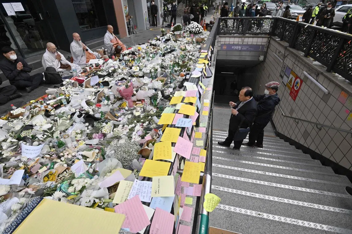 South Korean Buddhist monks (L) pray at a makeshift memorial for the victims of the deadly Halloween crowd surge, outside a subway station in the district of Itaewon in Seoul on November 3, 2022.