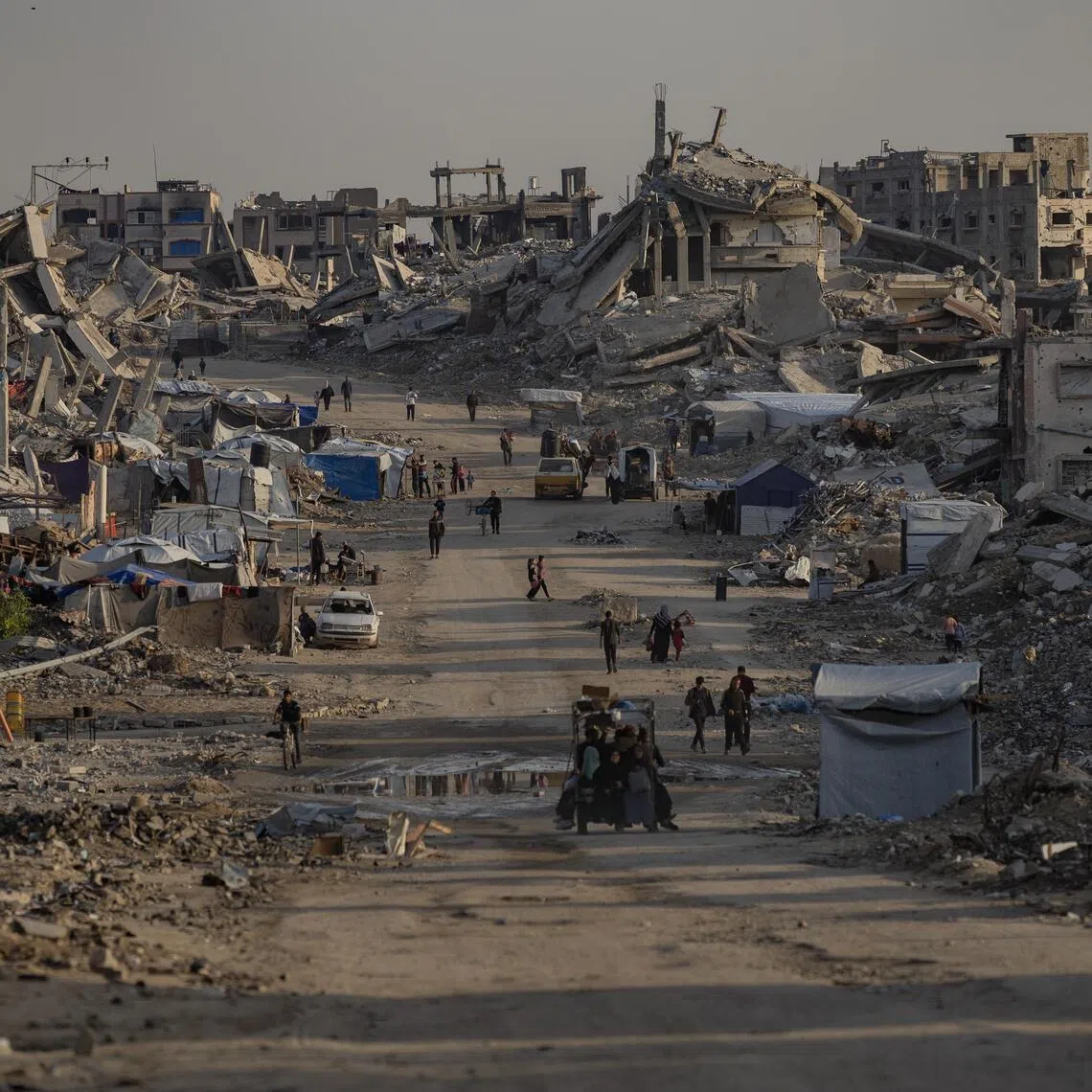 People walk between destroyed buildings in the Jabalia camp near Gaza City, on Nov 18, 2025.