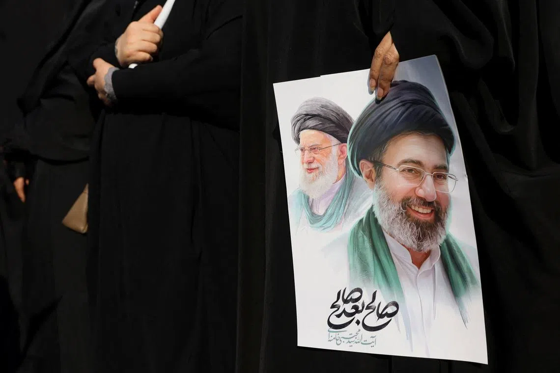 A woman holds an image of Iran's new supreme leader, Mojtaba Khamenei, alongside late Iranian Supreme Leader Ayatollah Ali Khamenei, during a funeral ceremony for the Iranian military commanders who were killed in strikes, amid the U.S.-Israeli conflict with Iran, in Tehran, Iran, March 11, 2026. Majid Asgaripour/WANA (West Asia News Agency) via REUTERS/File Photo