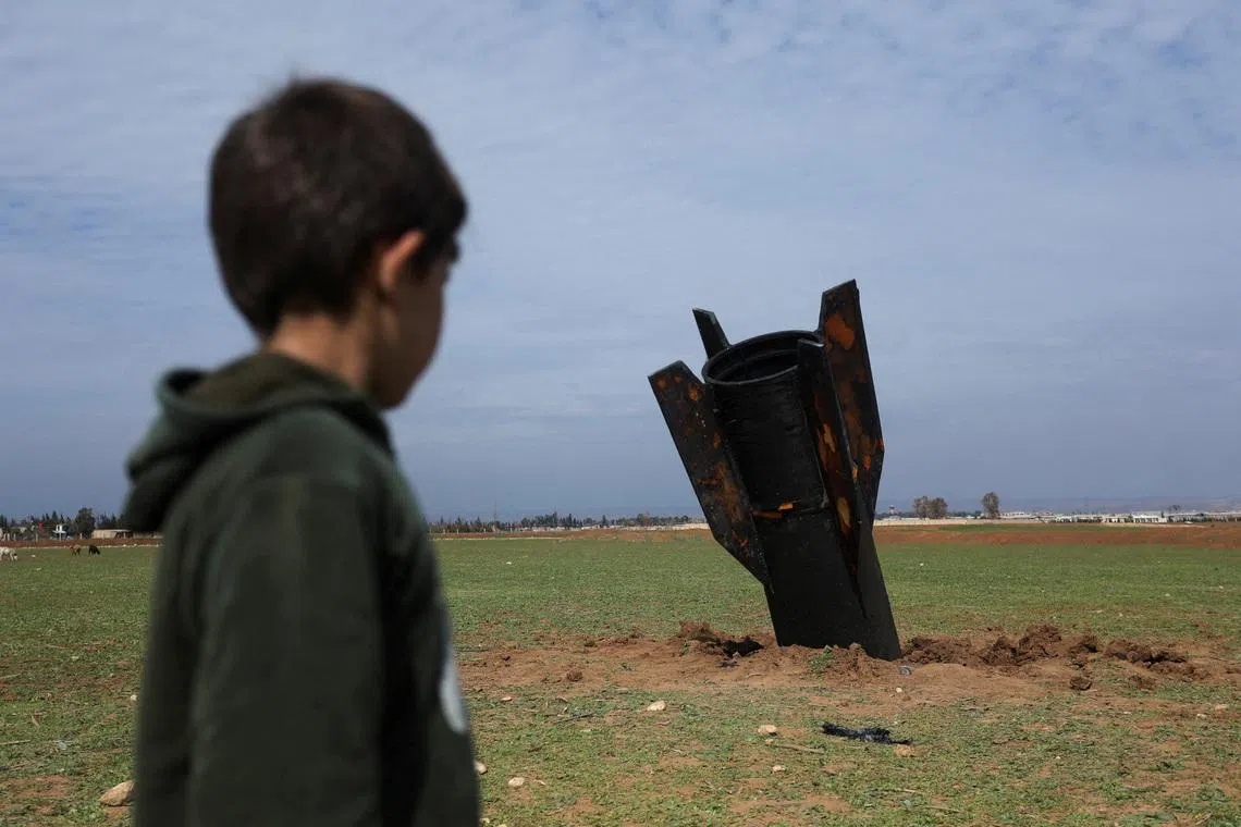 A child standing next to a missile after it fell near Qamishli International Airport, amid the U.S.-Israeli conflict with Iran, in Qamishli, Syria, on March 4, 2026.