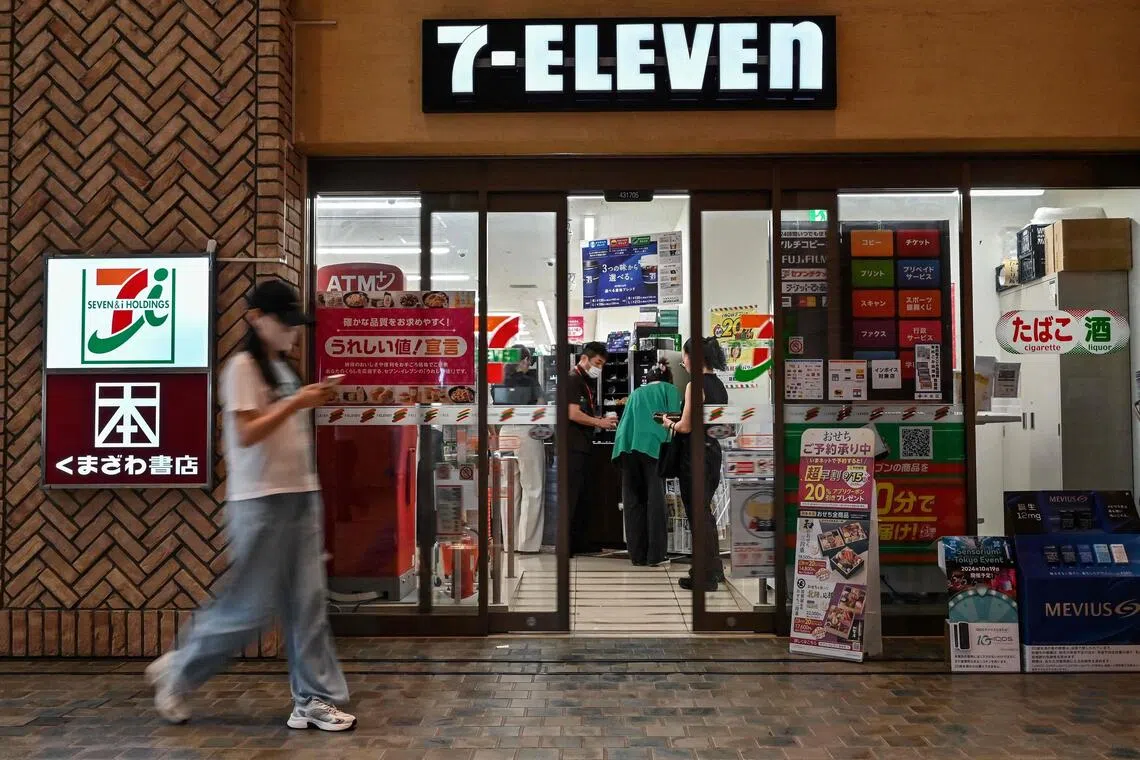 (FILES) This file photo taken on September 13, 2024 shows a woman walking past a 7-Eleven convenience store in Tokyo. Shares in the Japanese owner of 7-Eleven were down 9.45 percent on the Tokyo Stock Exchange on July 17, 2025 after Canadian rival dropped its almost 50-billion USD takeover bid. (Photo by Richard A. Brooks / AFP)