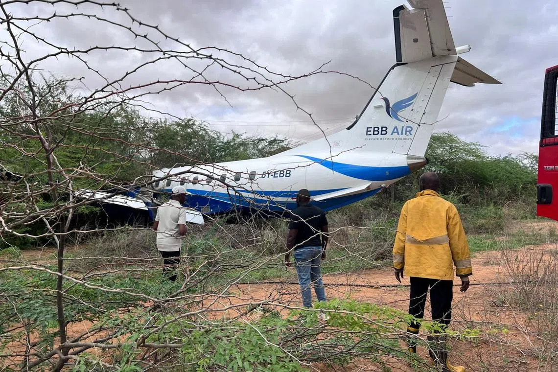 Rescuers walk towards an Embraer plane, operated by Kenyan carrier EBB Air, on a thicket after it overran the runway while landing in Mandera, Kenya, April 24, 2026. REUTERS/Stringer