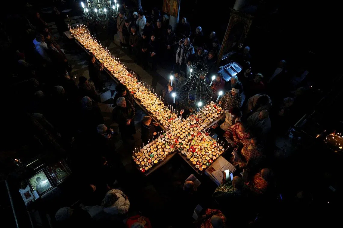 Worshippers gathering around candles stuck to jars with honey during a religious mass to mark the day of Saint Haralampi, the Orthodox patron saint of beekeepers, in the church of the Presentation of the Blessed Virgin in Blagoevgrad, Bulgaria, Feb 10, 2025. 