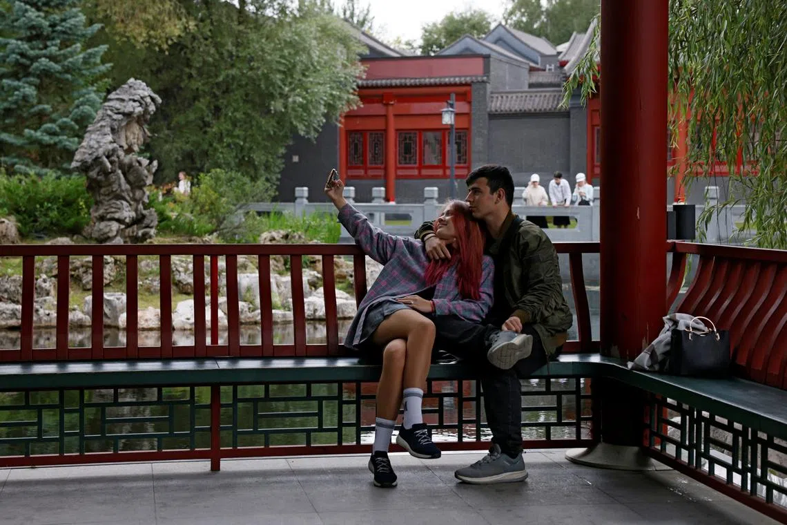 People take a selfie in the Chinese landscape park \"Huaming\" in Moscow, Russia August 19, 2025. REUTERS/Yulia Morozova