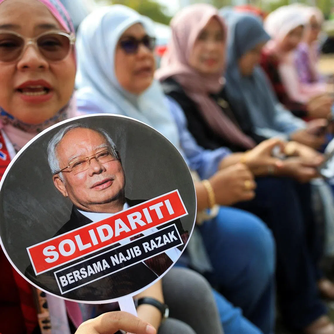 A supporter of former Malaysian Prime Minister Najib Razak holds a hand fan with a picture of Najib printed on it, outside the Malaysian Federal court, where his case is being heard at Putrajaya, Malaysia, August 13, 2025. REUTERS/Hasnoor Hussain